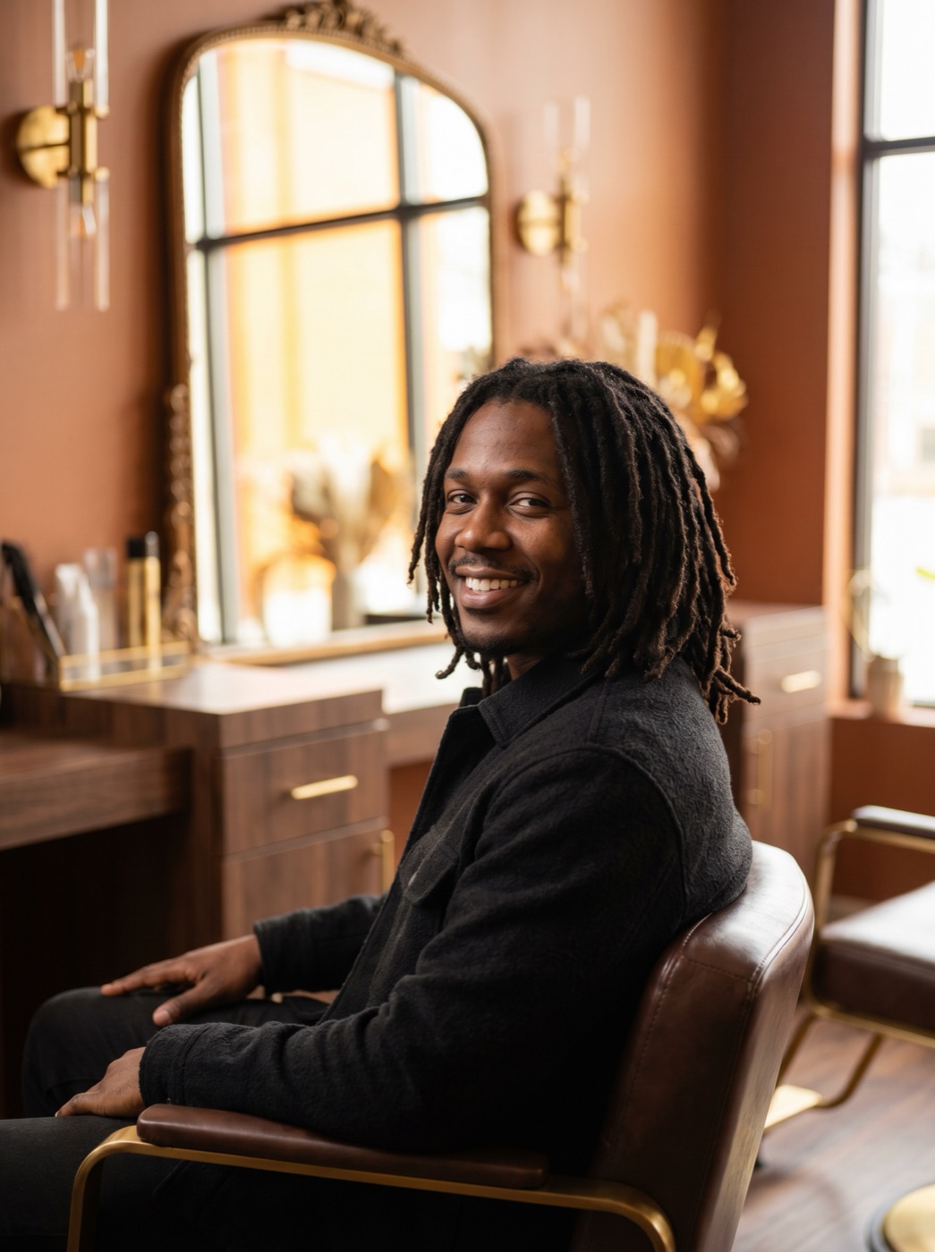 Black man with healthy mid-length traditional locs, relaxed and smiling, at DreamLocs Nashville